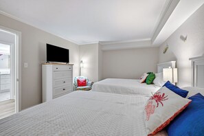 Ein Schlafzimmer mit zwei Betten, einem Schminktisch, einem Fernseher und einem Sessel.