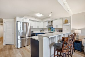 Eine moderne Küche mit einem Edelstahlkühlschrank, einem integrierten Wasserspender und einer zentralen Kochinsel mit Barhocker.