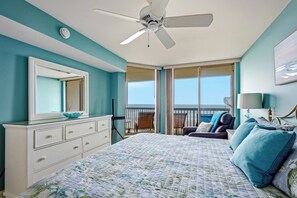 A bedroom with a bed, dresser, ceiling fan, and a view of the ocean. - Emerald Cove 4A - Oceanfront 4Br Condo (North Myrtle Beach)