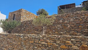 A stone wall with a rustic building structure on top. - Alkinoi Residences (Sifnos)