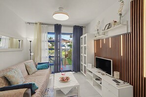 Ein modernes Wohnzimmer mit einer Couch, einem Fernseher und einem Esstisch mit einer Schüssel Essen.