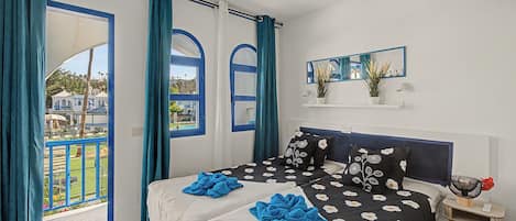 Un dormitorio con una cama, una mesita de noche, un espejo y vistas al exterior.