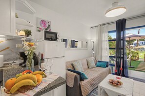 Ett kompakt bostadsutrymme med ett litet kök, en matplats och en sittgrupp med utsikt.