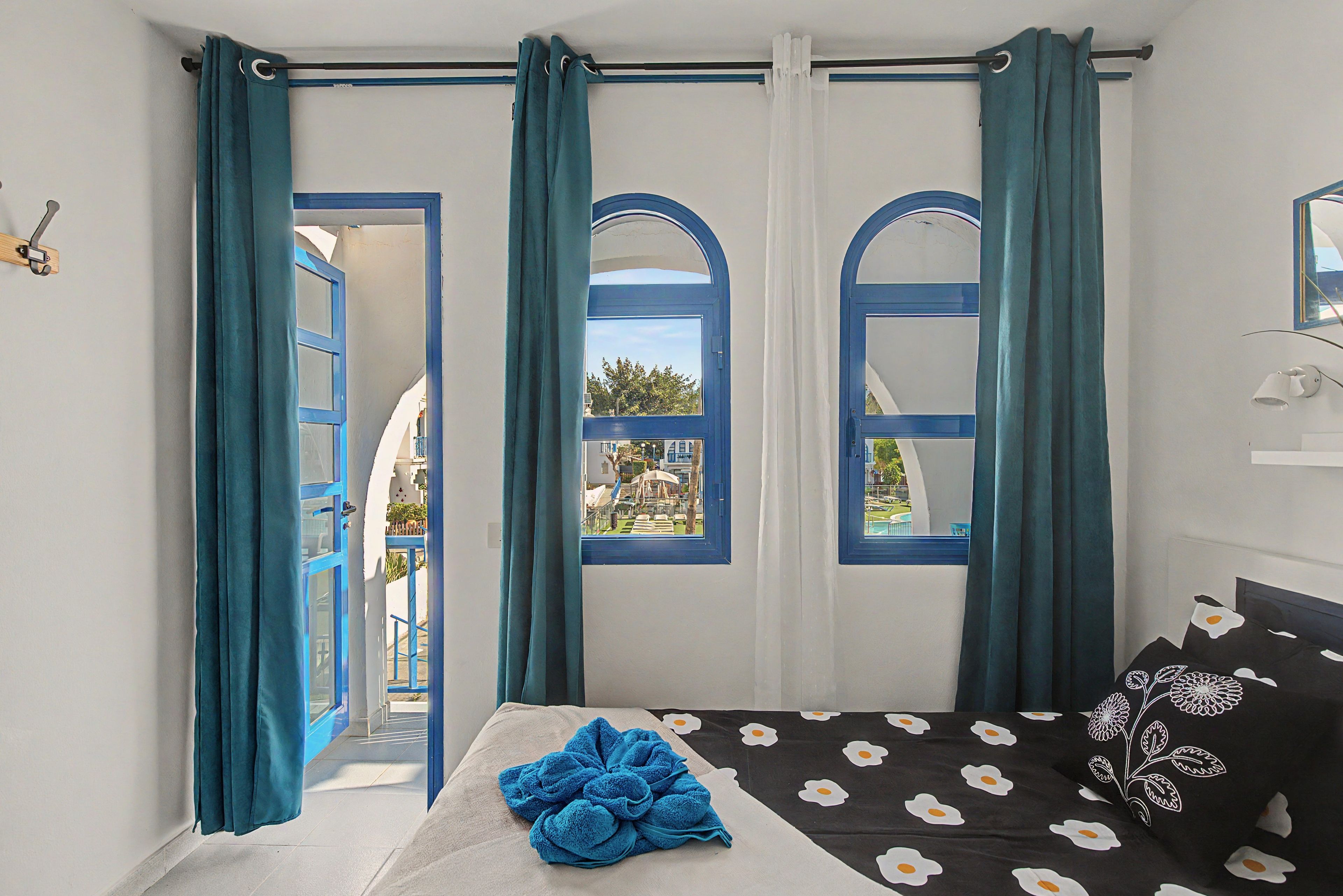 Ein Zimmer mit einem Bett, einem Vorhangfenster und Blick nach außen.