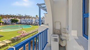 A balcony with a pool, lounge chairs, and a view of a residential area. -  'Casa Romantico - Playmar' with Shared Pool, Private Terrace and Wi-Fi (Maspalomas)