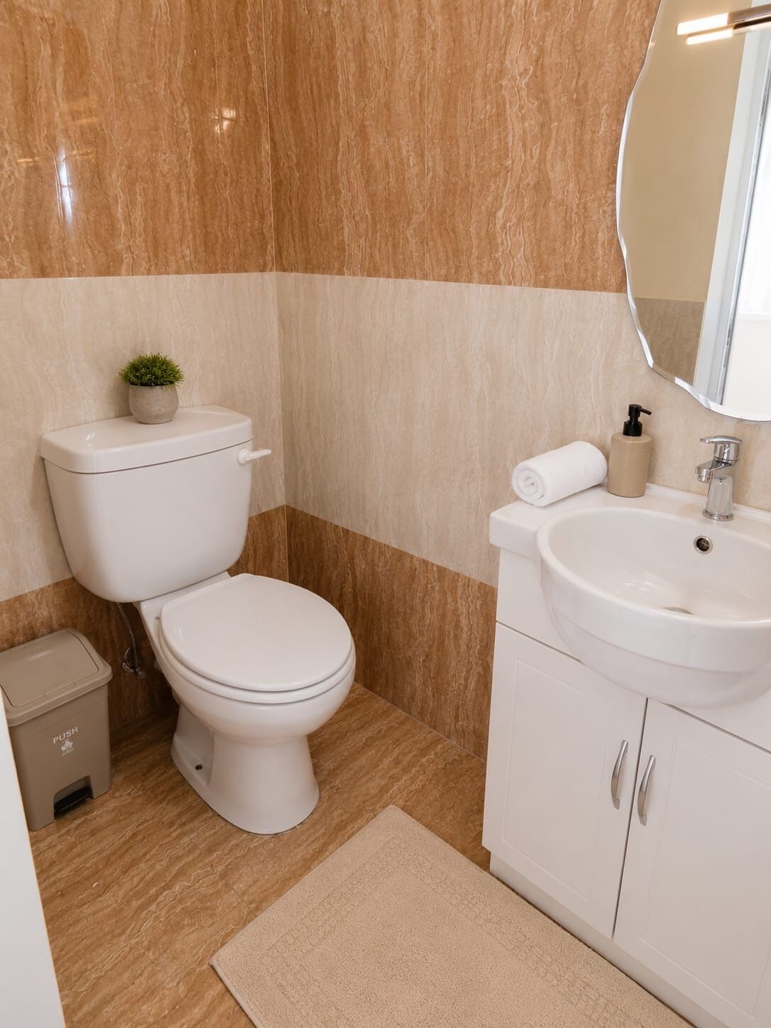 A bathroom with a toilet, sink, and mirror.