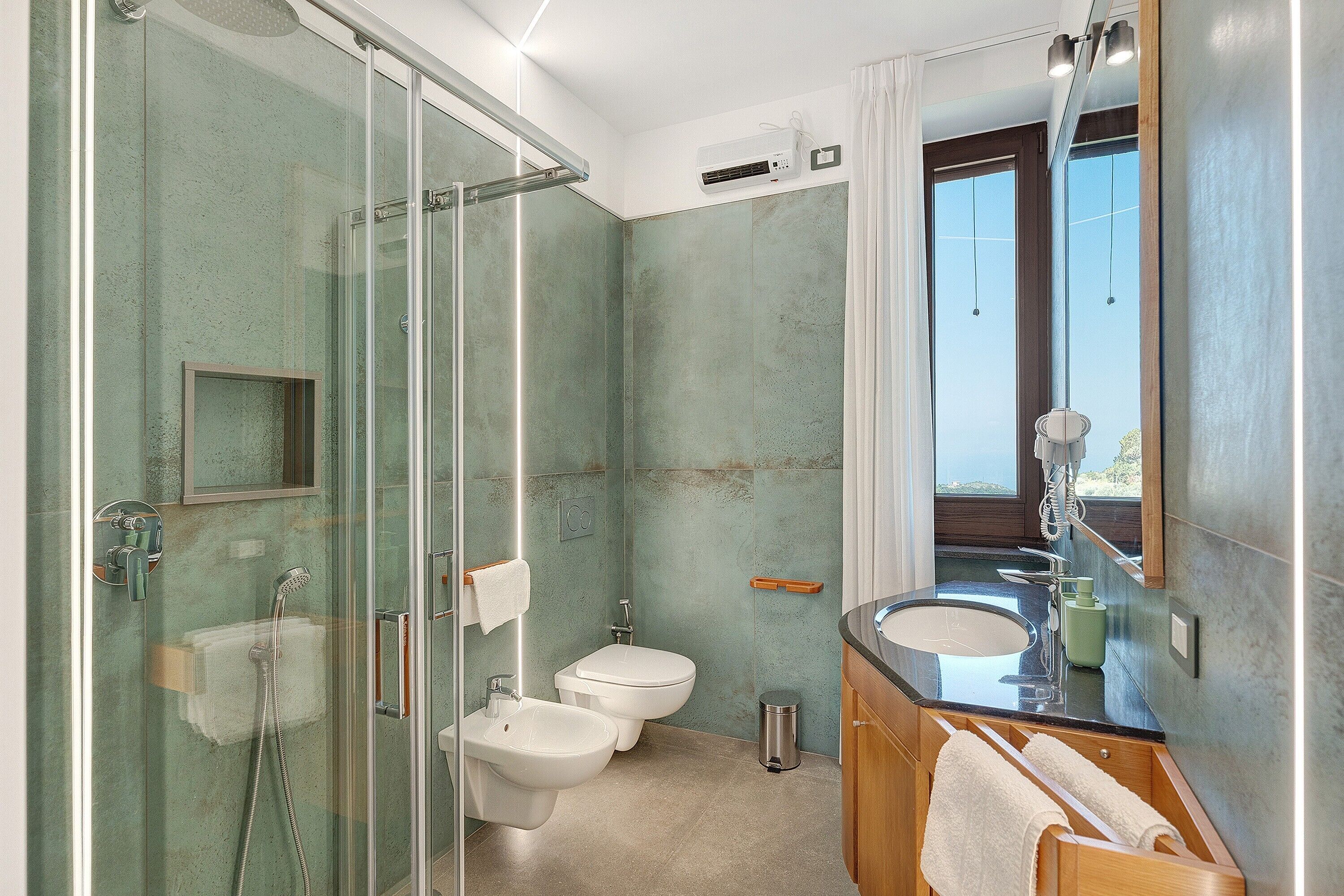 Un bagno con doccia vetro-ceramica, un water, un lavandino e uno specchio.