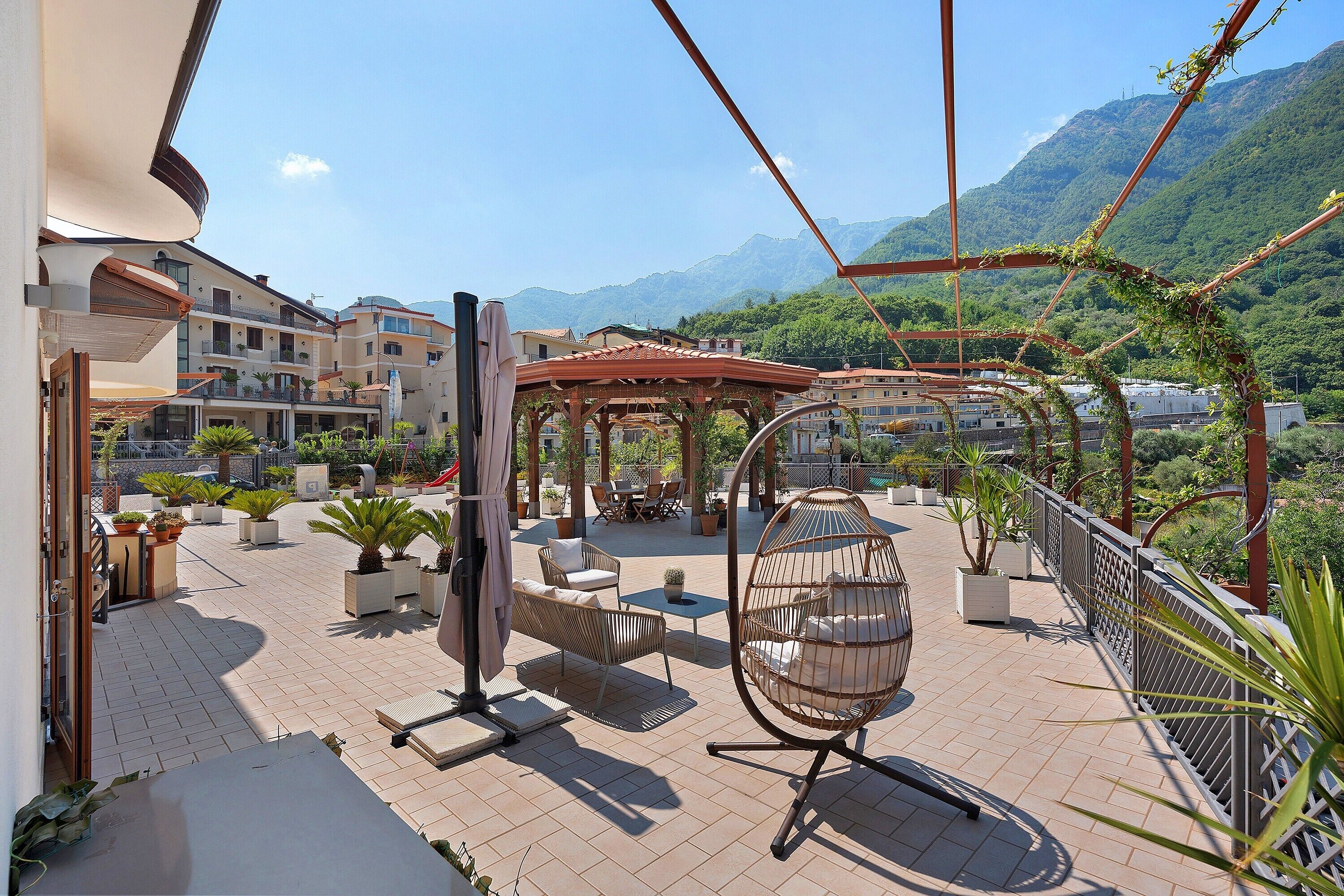 Eine Terrasse mit Gartenmöbeln, einer Pergola und Blick auf eine Berglandschaft.