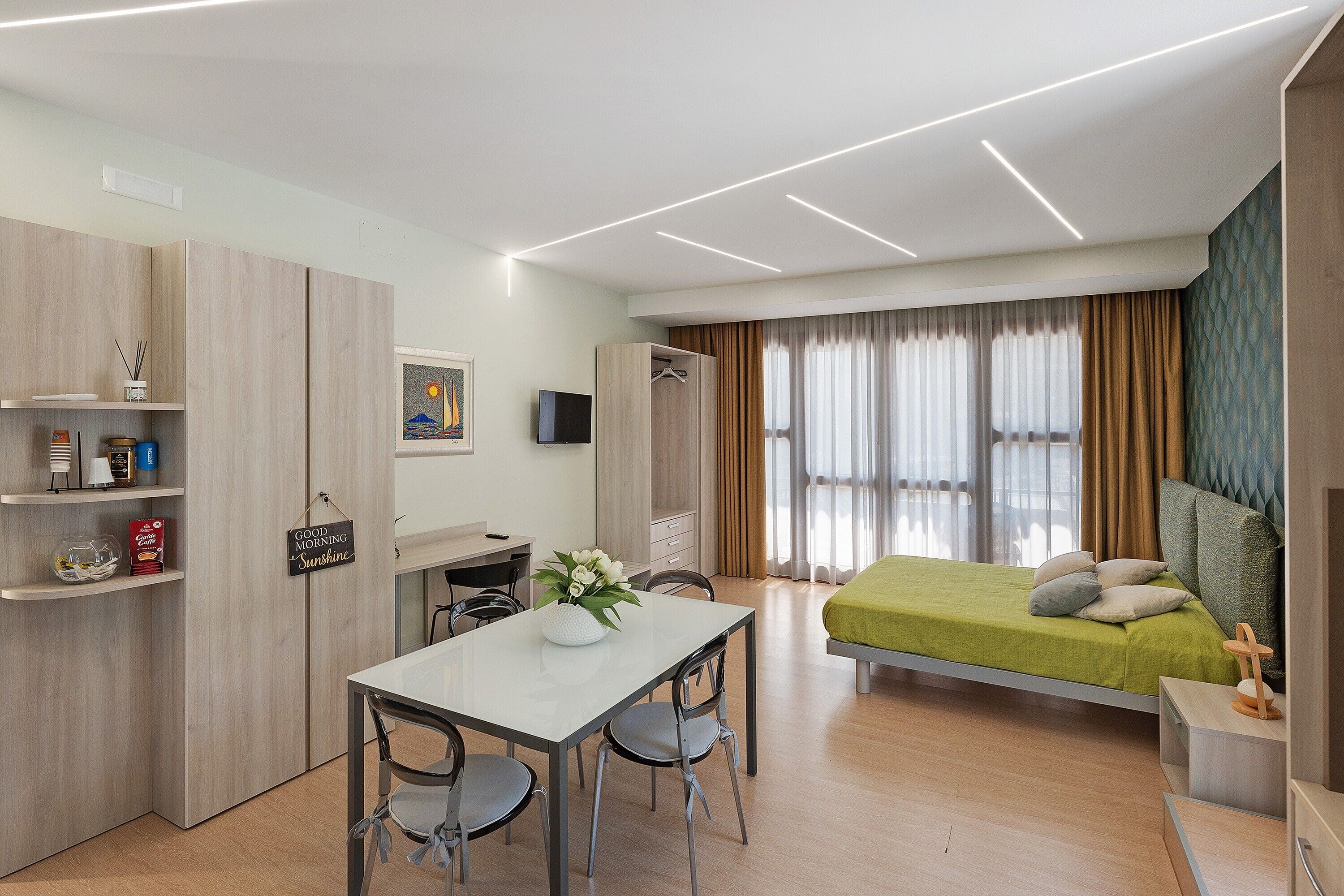 Une chambre d’hôtel moderne équipée d’un lit, d’un bureau, d’une chaise, d’une télévision et d’une armoire.