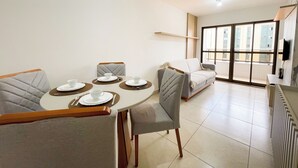 Ein modernes Wohnzimmer mit Essbereich, einer Couch und einem an der Wand befestigten Fernseher.