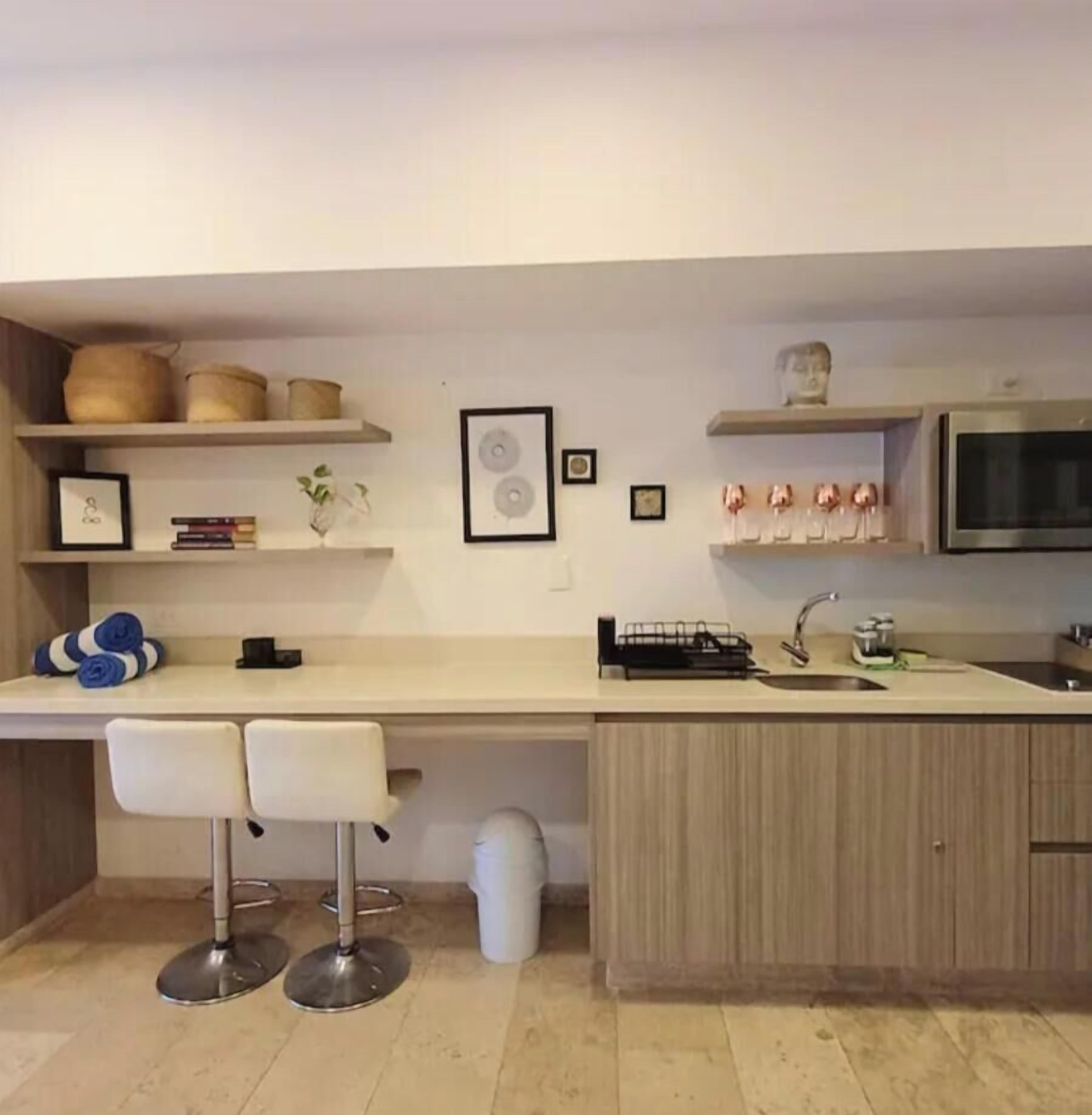 A modern kitchen with a built-in microwave, a sink, and a bar stool seating area.