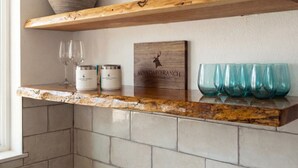 Un piano di lavoro in cucina con ripiano in legno, due contenitori, un cartello in legno e quattro bicchieri.