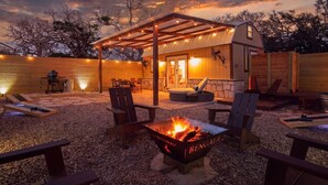 Un patio esterno accogliente con un braciere, posti a sedere e una zona riparata con luci decorative.