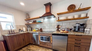Una cucina con mobili in legno, lavastoviglie in acciaio inossidabile, microonde e forno integrato.