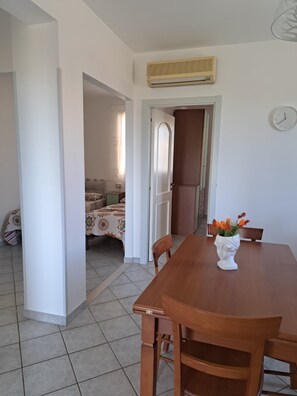 Ein Essbereich mit Holztisch, Stühlen, einer Vase mit Blumen, einer Uhr und einer Klimaanlage an der Wand.