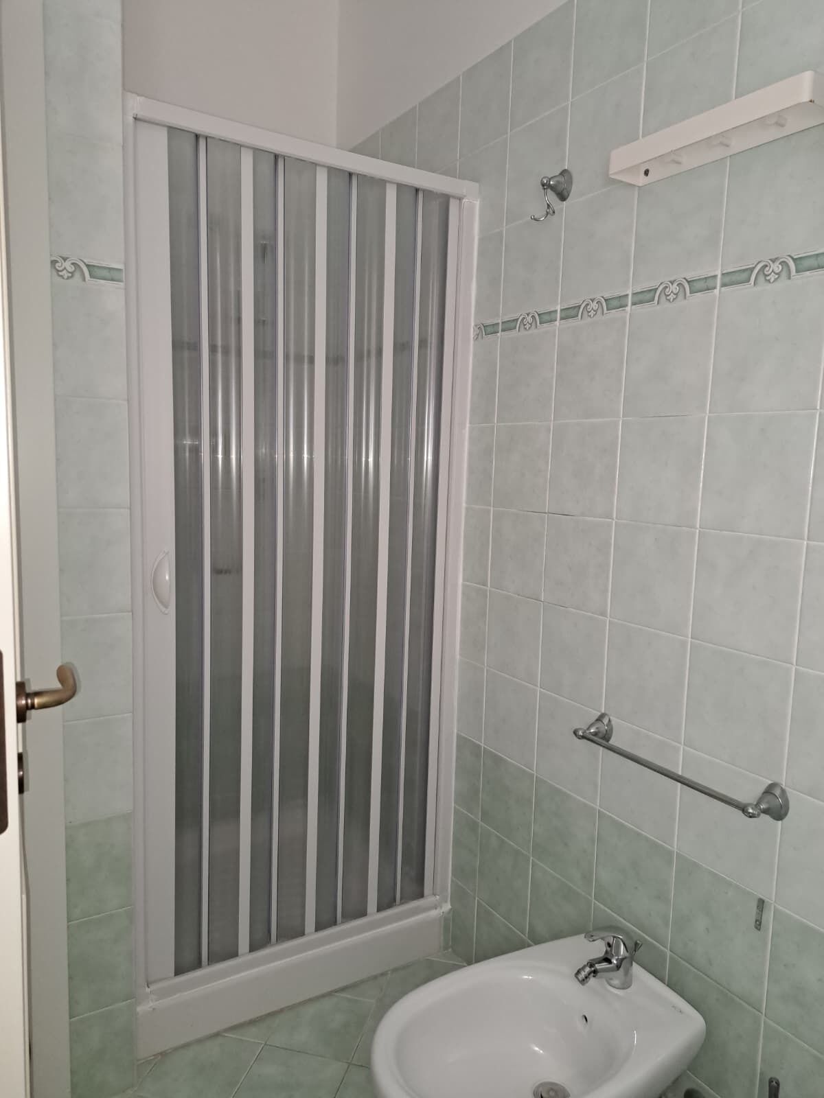 Une salle de bain avec une douche, un lavabo et un porte-serviettes.