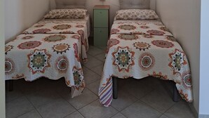 A room with two beds, a small cabinet, and a painting on the wall. - The Residences 5 (Marina di Modica)
