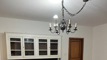 A dining area with a glass-top table, black chairs, and a white cabinet with glass doors.
