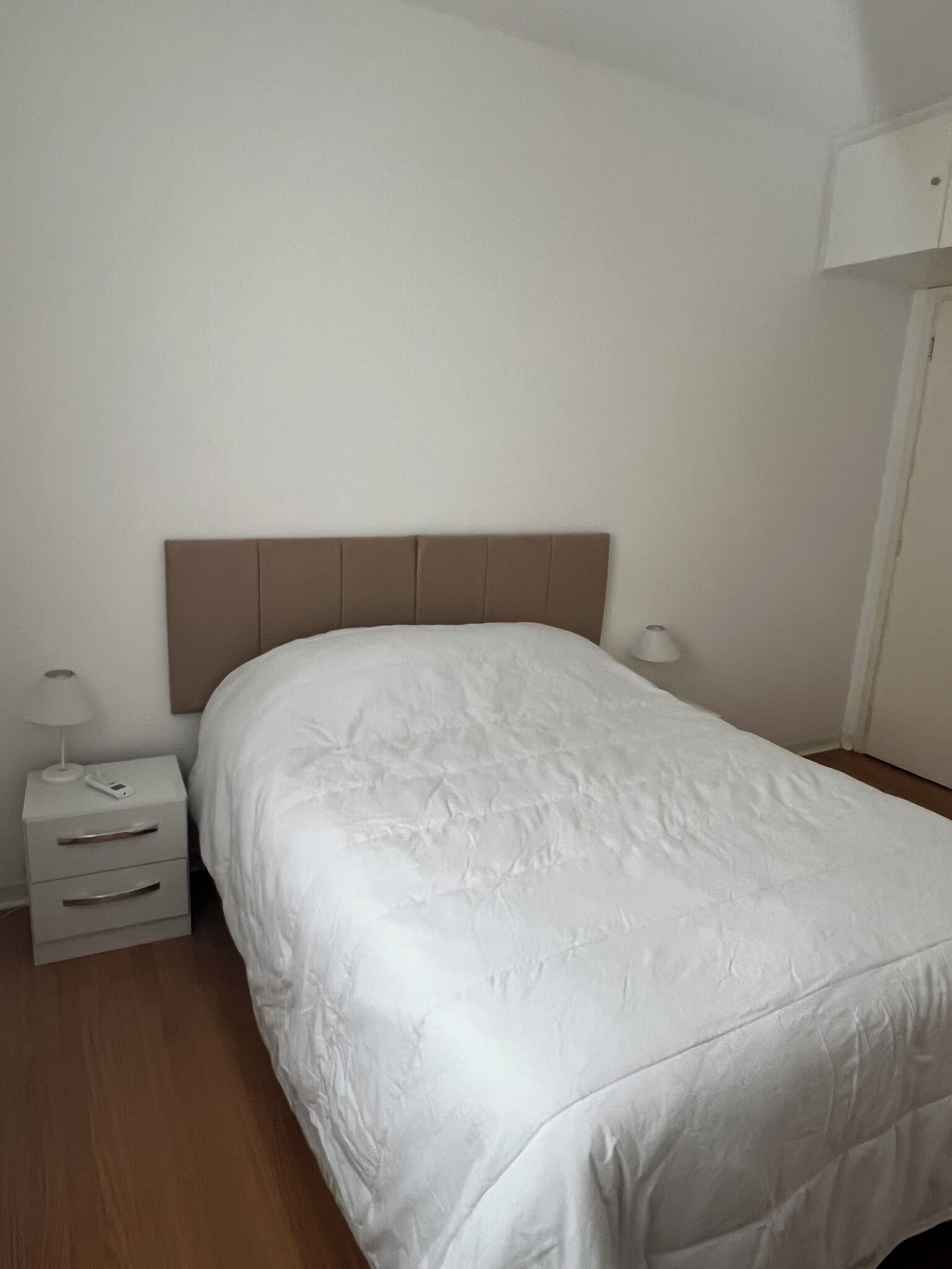 Une chambre à coucher avec un lit, une table de chevet, une lampe et une armoire.