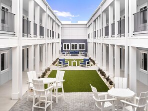 Un atrio moderno con un patio central, muebles blancos y una zona con sofá azul.