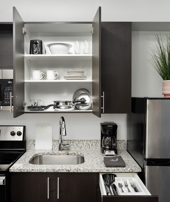 Una cocina moderna con horno empotrado, cafetera y refrigerador de acero inoxidable.