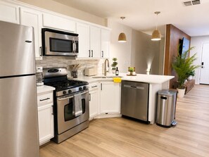 Una cucina moderna con elettrodomestici in acciaio inossidabile, mobili bianchi e pavimento in legno.
