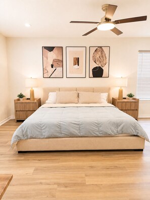 Un dormitorio con cama, dos mesitas de noche, ventilador de techo y decoración en la pared.