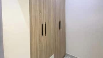 Een kamer met een grote kledingkast, een vloer met marmerprint en een plafondlamp.