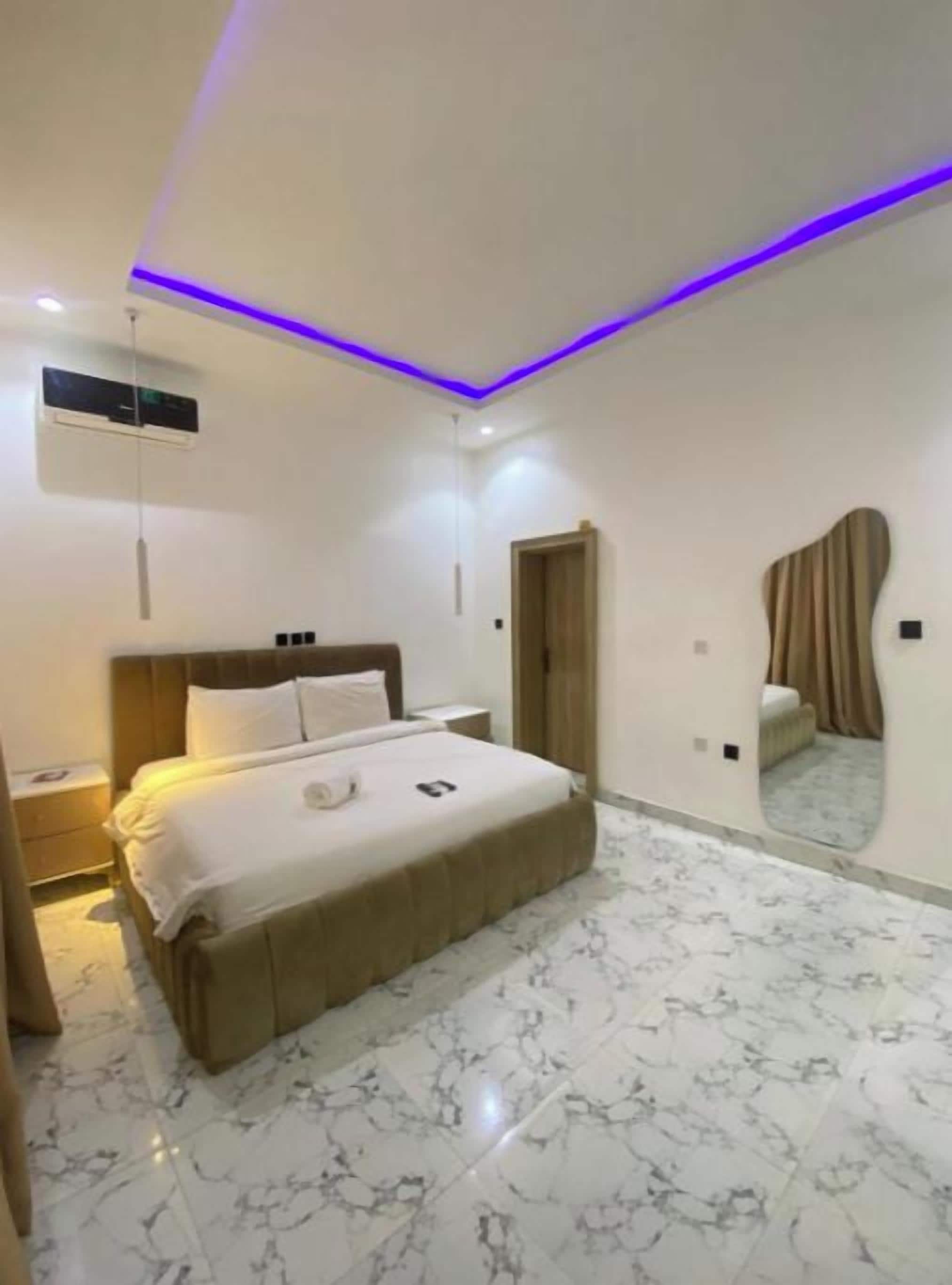 A modern bedroom with a large bed, a mirror, and a ceiling light fixture.