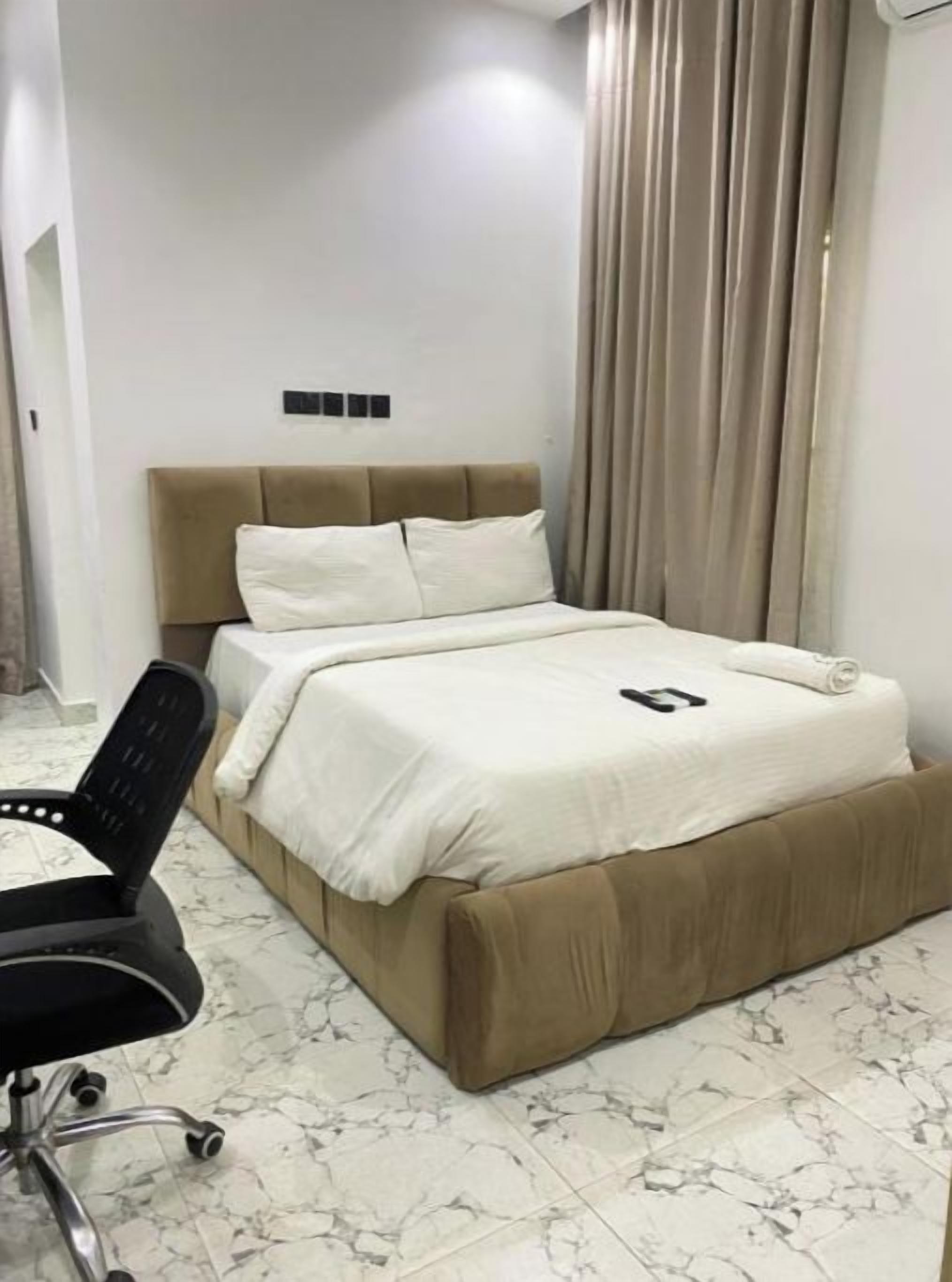 Een slaapkamer met een bed, een stoel en een marmeren vloer.