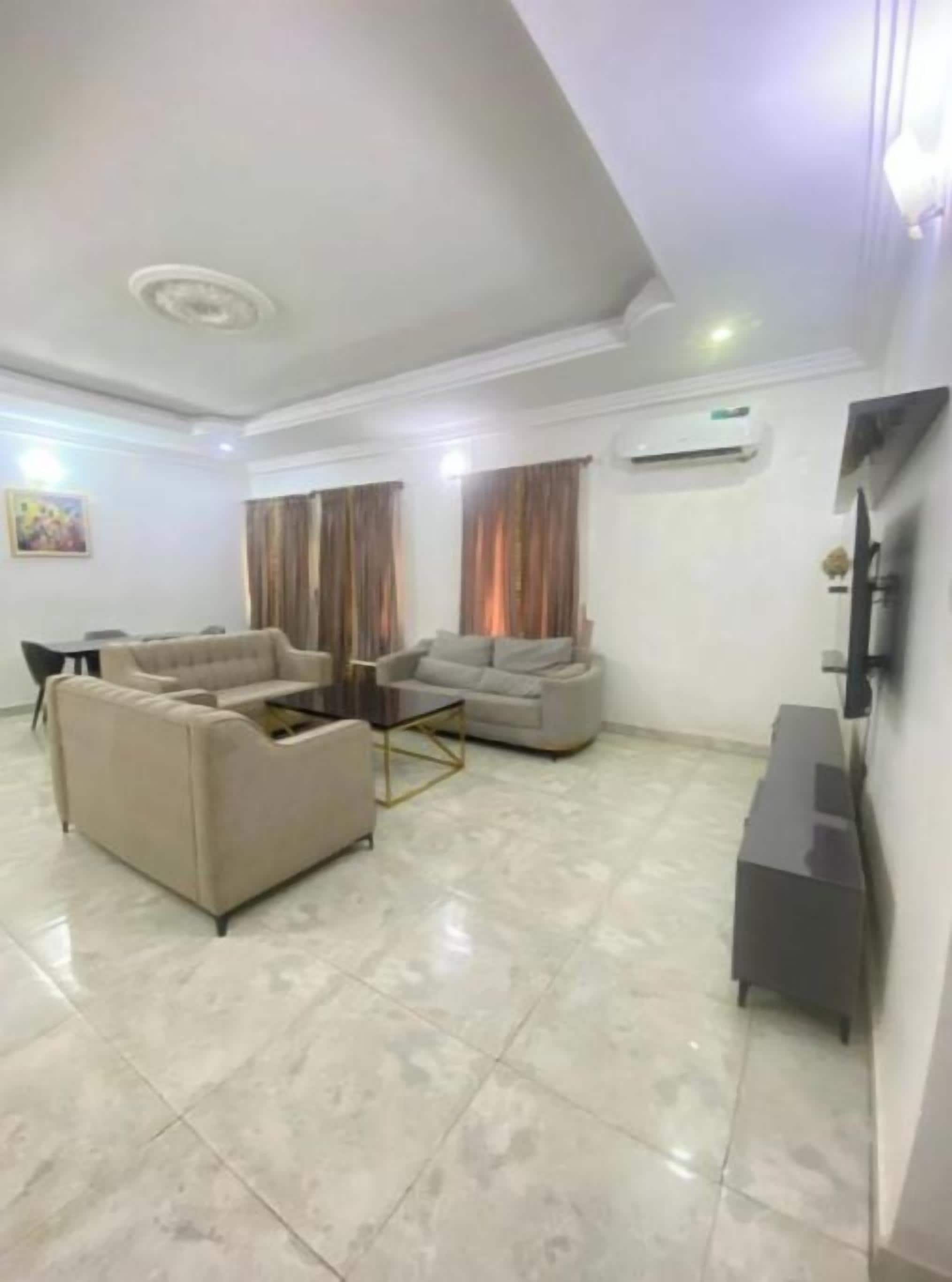 A living room with a sofa set, a coffee table, and a flat-screen TV against the wall.