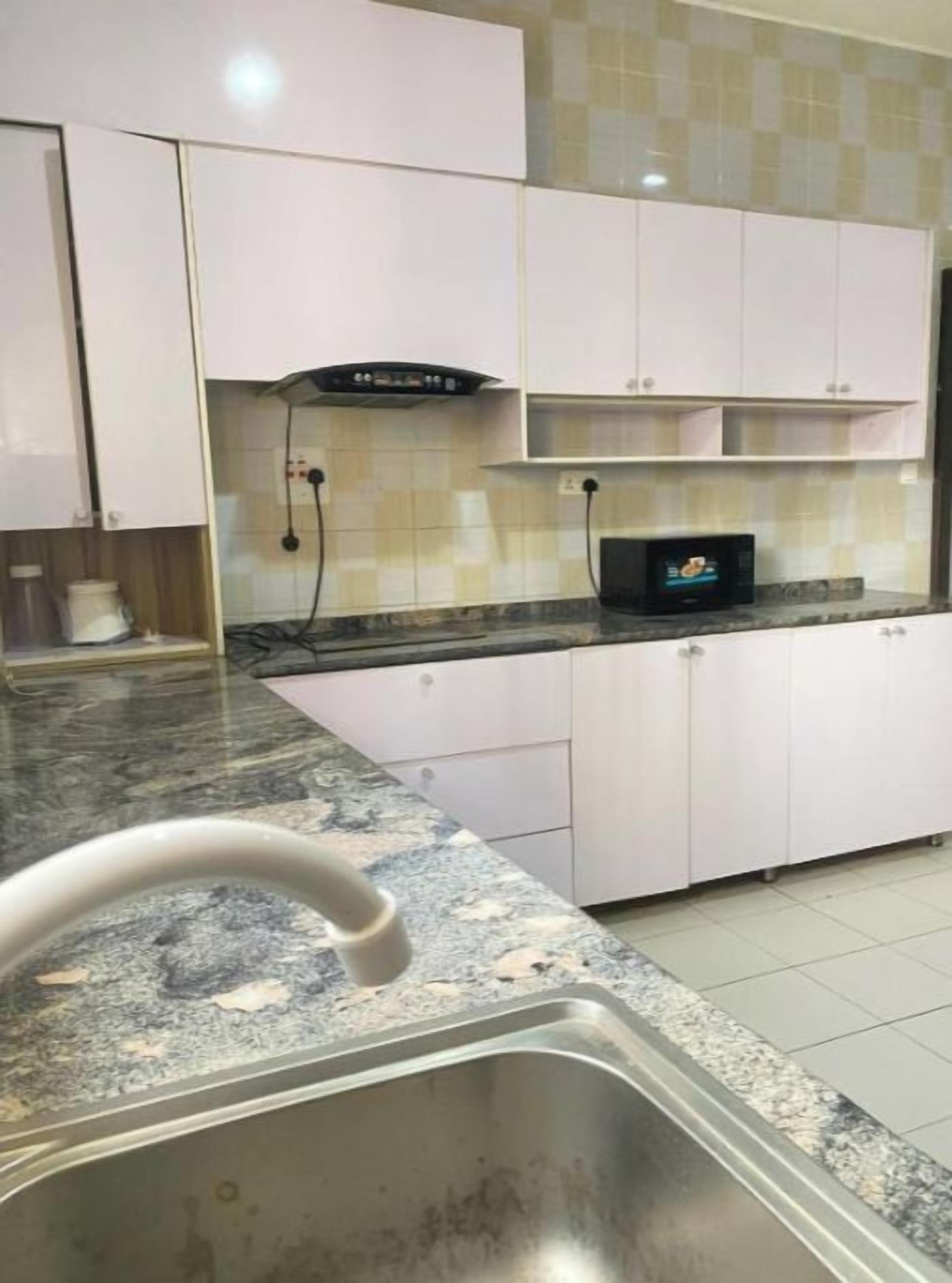 Een keuken met witte kasten, een granieten aanrechtblad en een roestvrijstalen spoelbak.