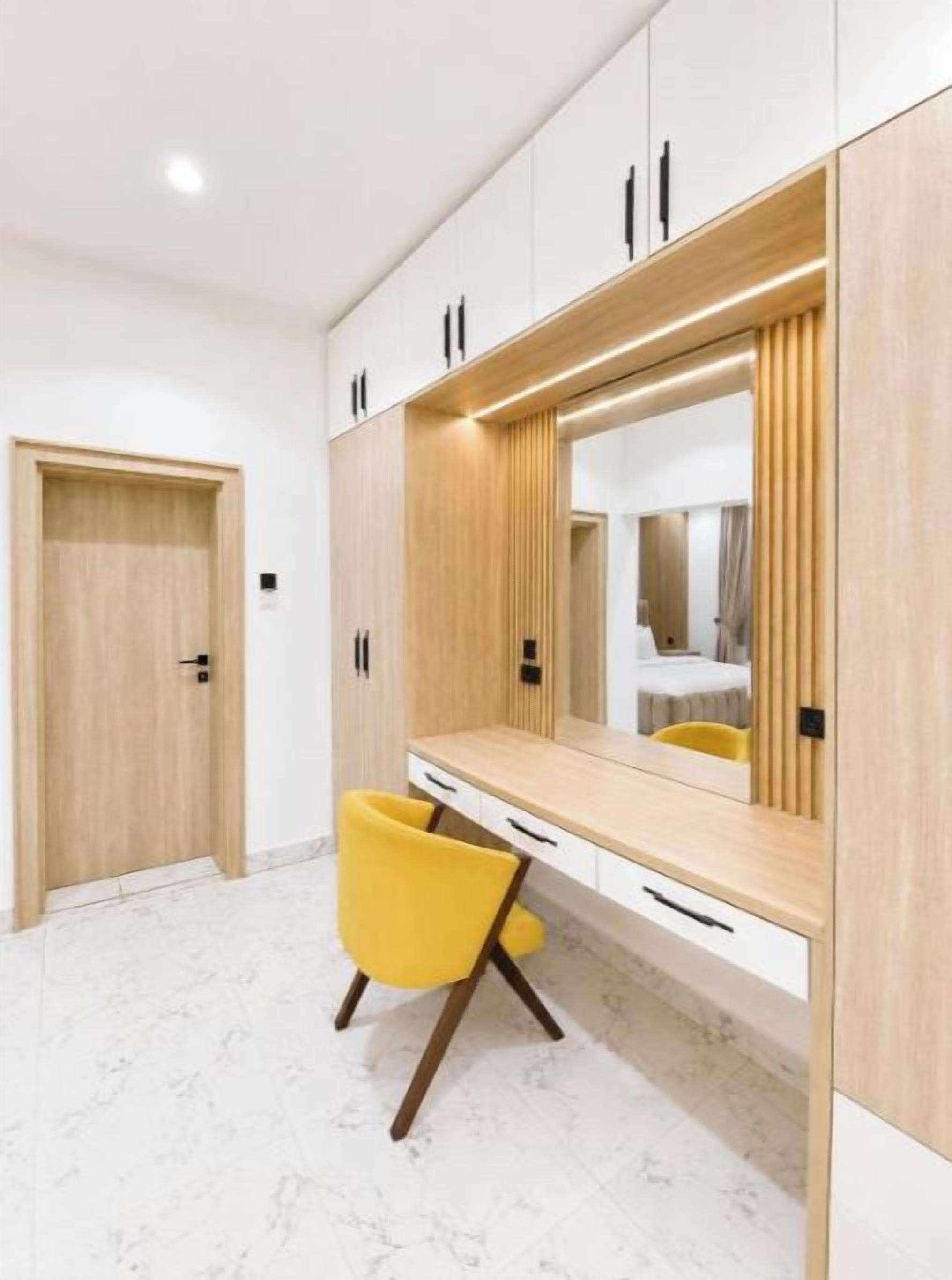 A modern bathroom with a vanity, mirror, and yellow chair.