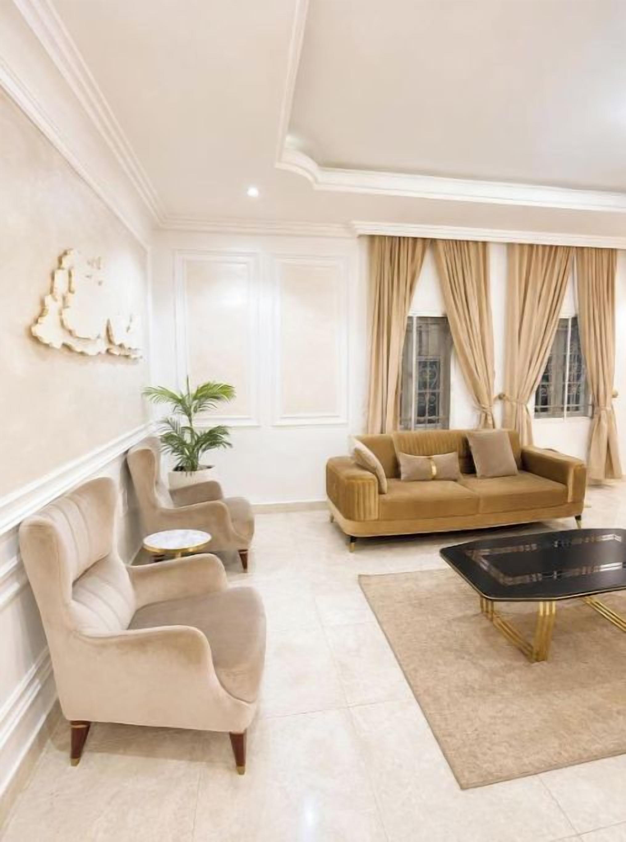 Una sala de estar con un sofá color beige, sillones, una mesa de centro y una planta en maceta.