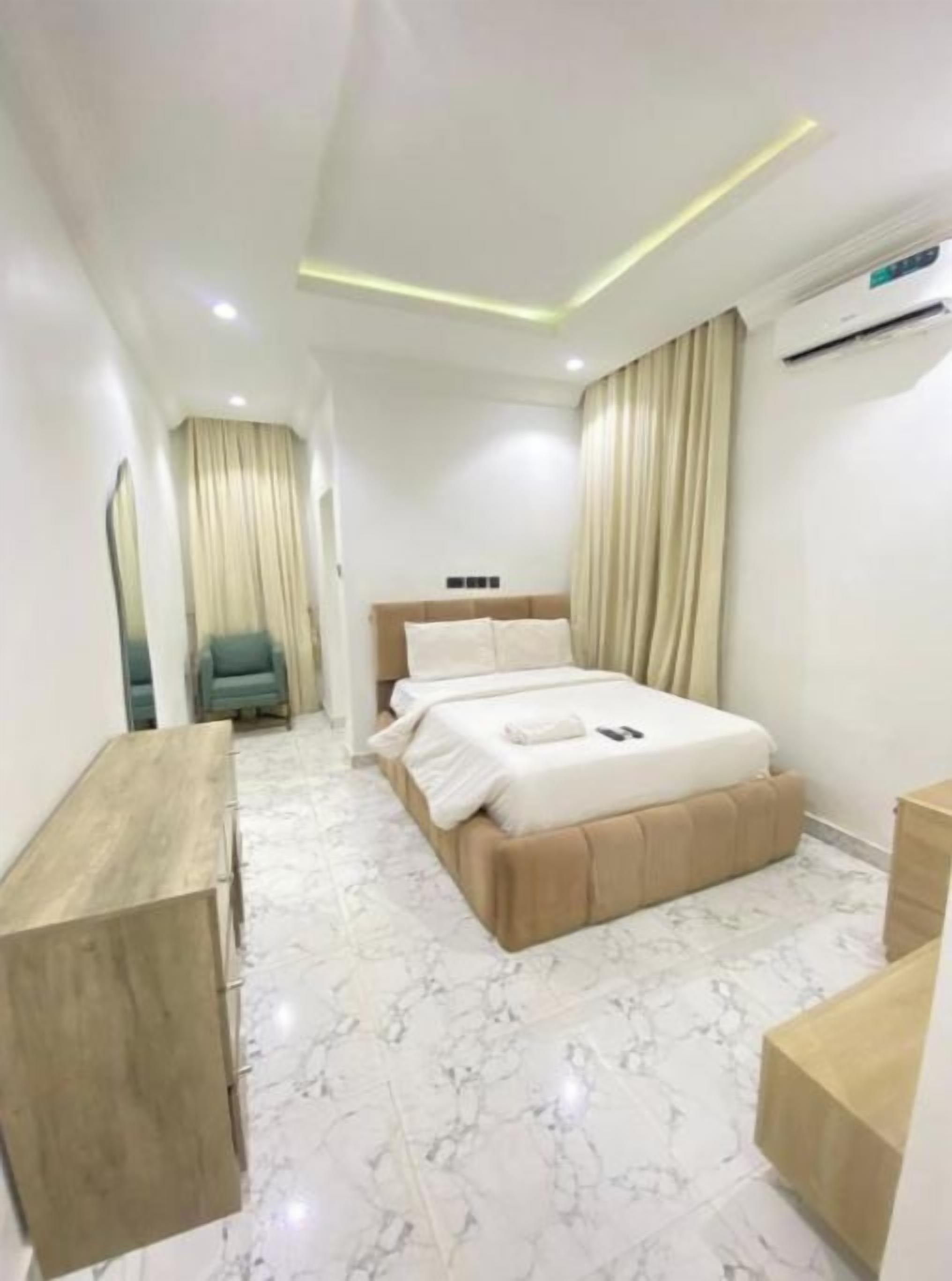 Ein modernes Hotelzimmer mit Bett, Nachttischen, einem Schreibtisch und einem Sessel.