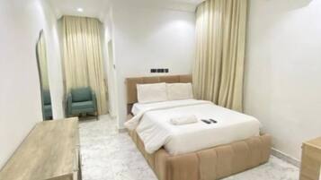 Ein modernes Hotelzimmer mit Bett, Nachttischen, einem Schreibtisch und einem Sessel.