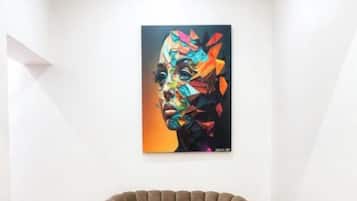 Ein Zimmer mit Holzboden, einem braunen Sofa, einem senfgelben Sessel und einem farbenfrohen abstrakten Gemälde an der Wand.