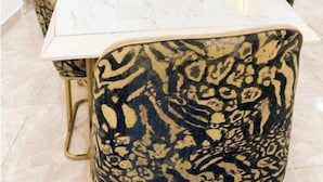 Ein Essbereich mit einem Marmortisch, gemusterten Stühlen und einem gerahmten Kunstwerk an der Wand.