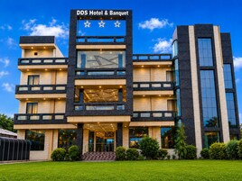A multi-story hotel with a modern design, featuring a prominent entrance with a staircase, large windows, and a sign reading 'DDS Hotel & Banquet'.