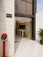 A modern bathroom with a glass entrance, marble flooring, and a red fire hydrant outside.