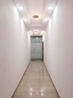 A narrow hallway with a tiled floor, white walls, and recessed lighting.