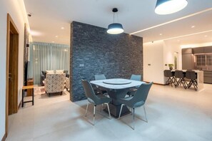 A modern dining area with a round table, chairs, and a stone accent wall. - Opulent Villa Nuwara Eliya (Nuwara Eliya)
