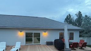 Ein Haus mit überdachter Terrasse, Sitzgelegenheiten im Freien und einem Grill.
