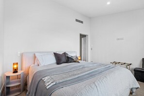 A modern bedroom with a bed, bedside tables, and a nightstand. - Aspen Ridge by MajorDomo | Fernhill Villa with Lake Views, Infrared Sauna, Spa Pool & Outdoor Fireplace (Queenstown)