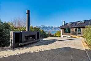A modern outdoor fireplace with a clear view of mountains in the background. - Aspen Ridge by MajorDomo | Fernhill Villa with Lake Views, Infrared Sauna, Spa Pool & Outdoor Fireplace (Queenstown)