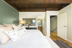 A bedroom with a bed, a bedside table, a mirror, and a view of a bathroom. - Waterfront Tahoe Keys Condo. Private Boat Dock, Lake Views & Family Friendly (South Lake Tahoe)