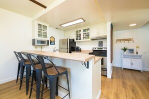 A kitchen with a central island, bar stools, a microwave, a refrigerator, and a stove. - Waterfront Tahoe Keys Condo. Private Boat Dock, Lake Views & Family Friendly (South Lake Tahoe)