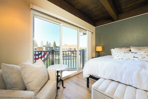 A hotel room with a bed, a small table, a sofa, and a balcony with a view of a body of water and buildings. - Waterfront Tahoe Keys Condo. Private Boat Dock, Lake Views & Family Friendly (South Lake Tahoe)