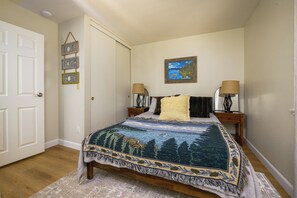 Ein Schlafzimmer mit einem Bett, zwei Nachttischen, einem Bild und einem an der Wand befestigten Schild.
