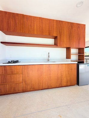 Una cocina moderna con armarios de madera, un lavamanos de acero inoxidable y un refrigerador empotrado.